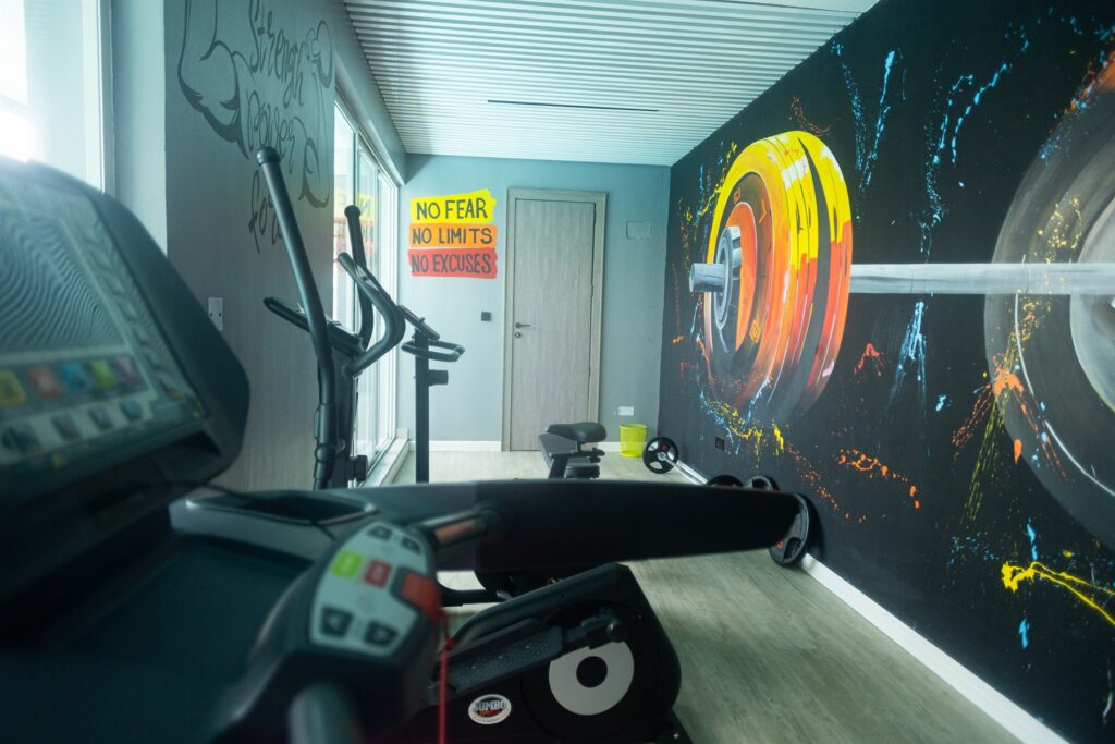 Brum Height 6: Residents' gym with cardio equipment and a weights mural